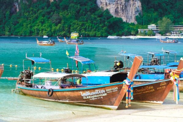 Relax on Thai Islands (1) Traditional long-tail boats anchored on a white sandy beach with towering limestone cliffs