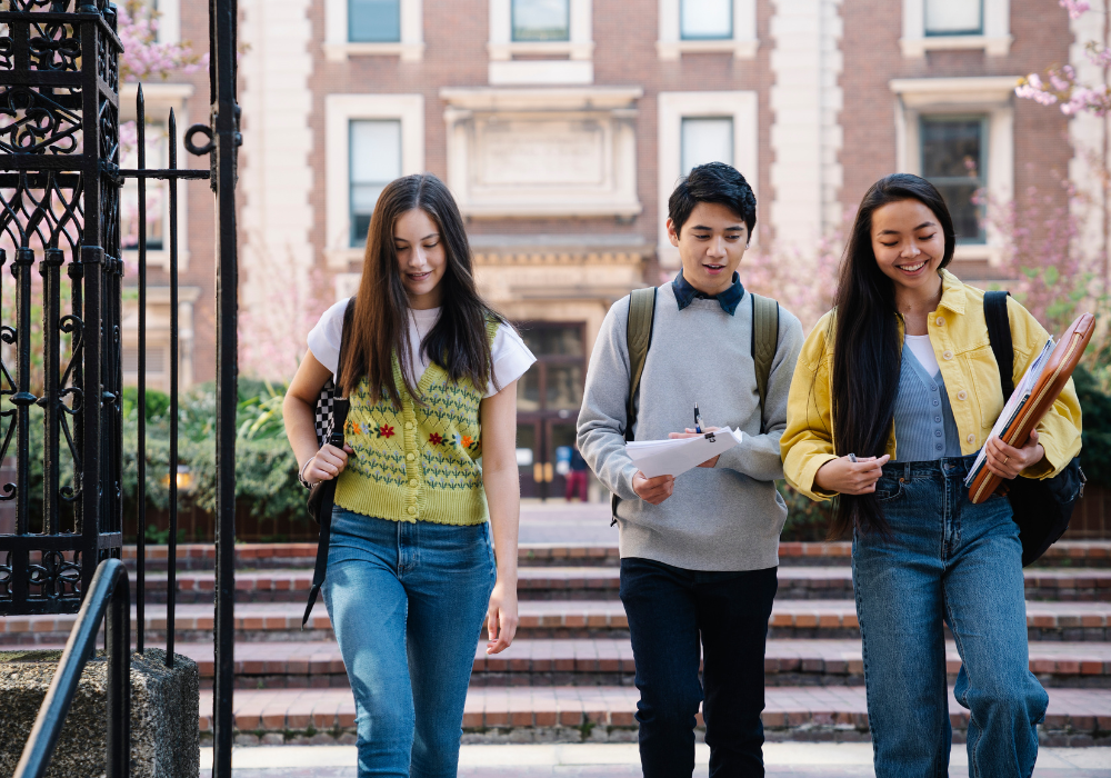 three-students-gallery Three students walking through the city, holding books